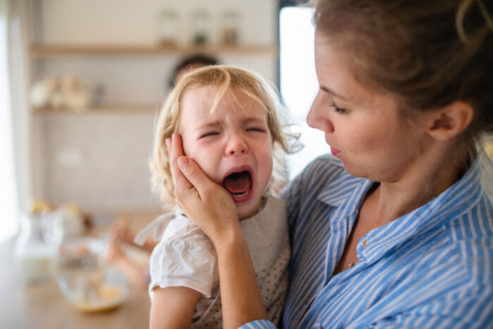 Image of child crying and behing held by a parental figure